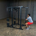 Body solid power rack with cables and male user.